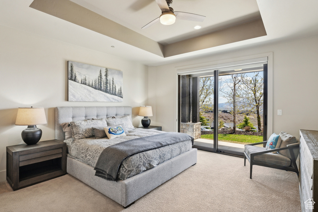 Carpeted bedroom with a tray ceiling, a ceiling fan, and access to exterior