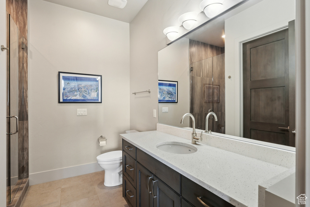 Bathroom featuring baseboards, toilet, a shower stall, tile patterned floors, and vanity