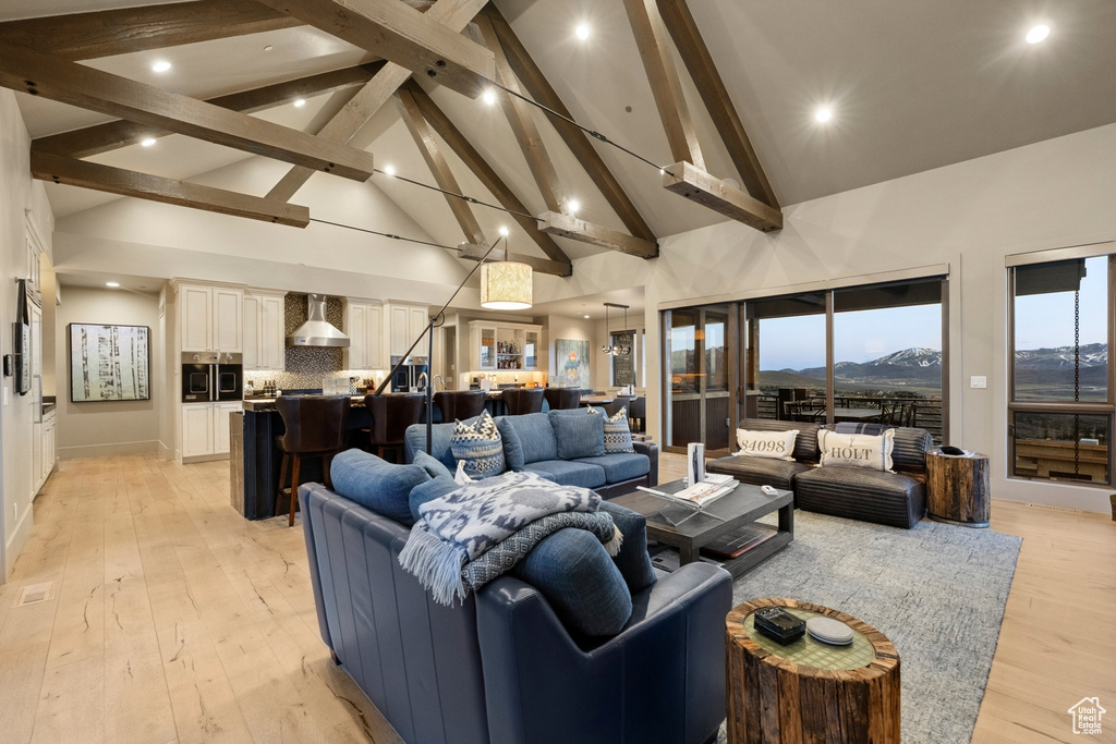 Living room featuring a mountain view, high vaulted ceiling, beamed ceiling, light wood-style floors, and recessed lighting