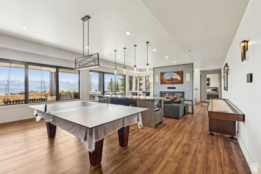 Rec room featuring baseboards, dark wood-style floors, a glass covered fireplace, and recessed lighting