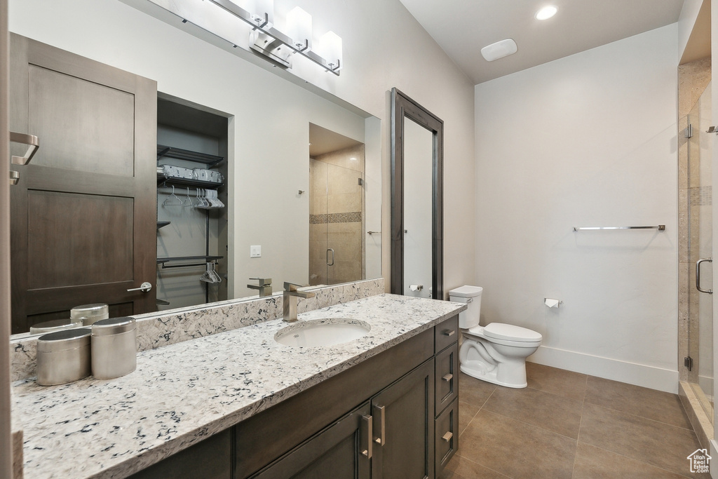 Bathroom featuring toilet, vanity, tile patterned flooring, a shower stall, and baseboards