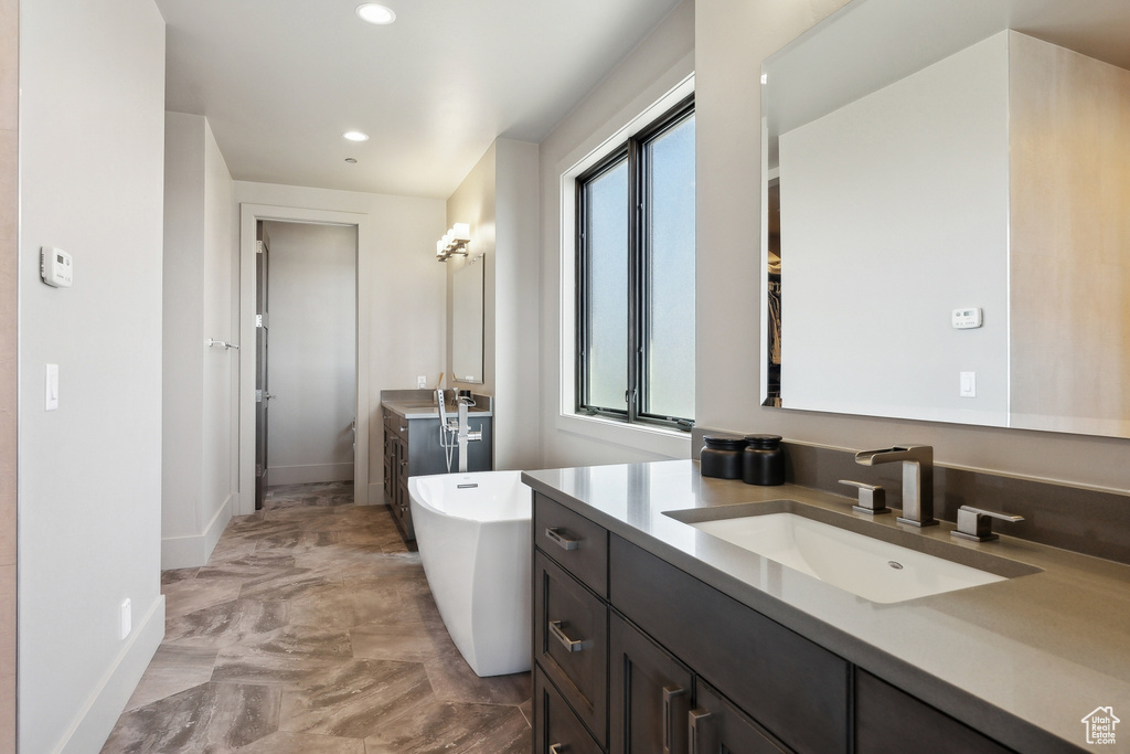 Full bath featuring a sink, baseboards, a freestanding tub, marble finish floor, and recessed lighting