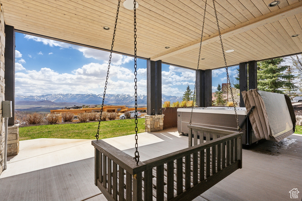 View of patio with a mountain view and a hot tub