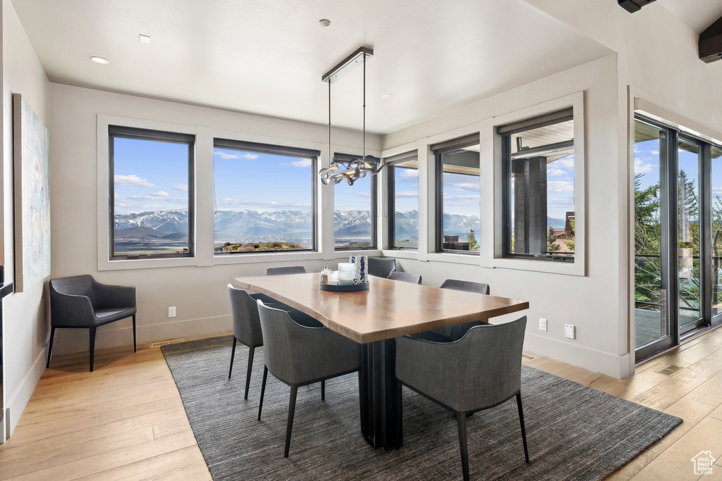 Dining area with an inviting chandelier, baseboards, light wood-type flooring, and a mountain view