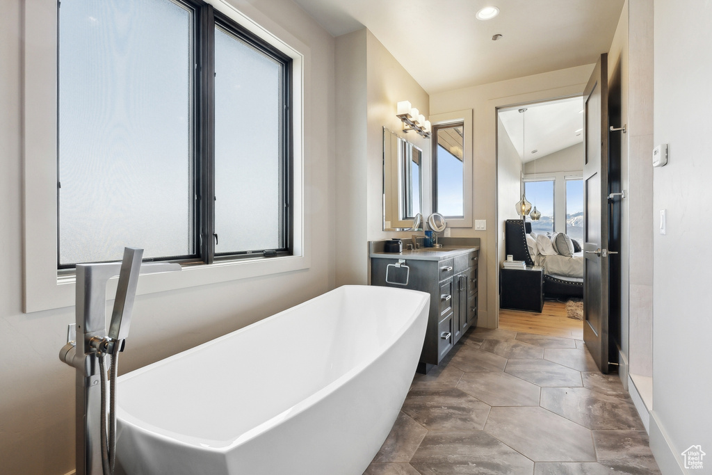 Bathroom with lofted ceiling, recessed lighting, ensuite bath, vanity, and a freestanding tub