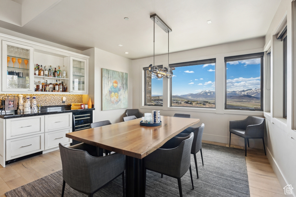 Dining area with bar, recessed lighting, beverage cooler, baseboards, and light wood-style floors