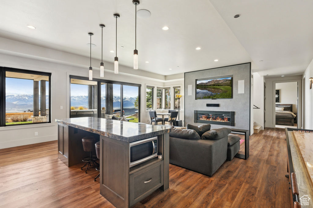 Kitchen with stainless steel microwave, dark wood finished floors, a kitchen island, and recessed lighting
