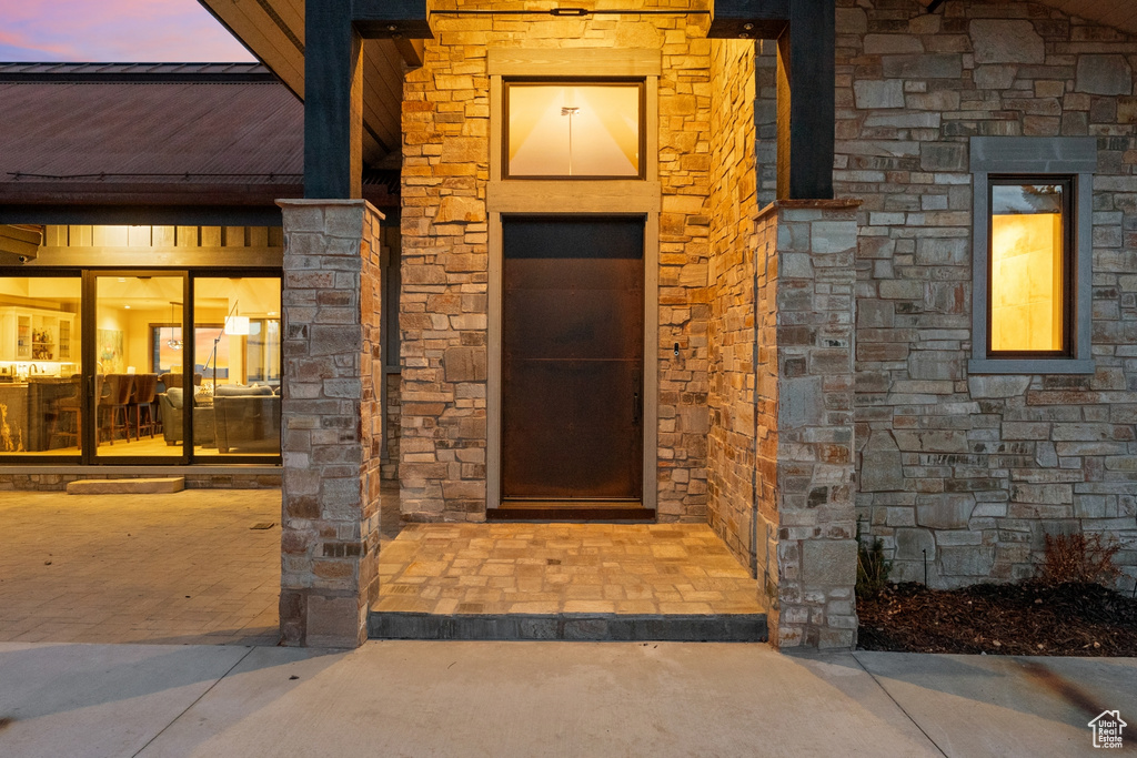 Exterior entry at dusk with stone siding