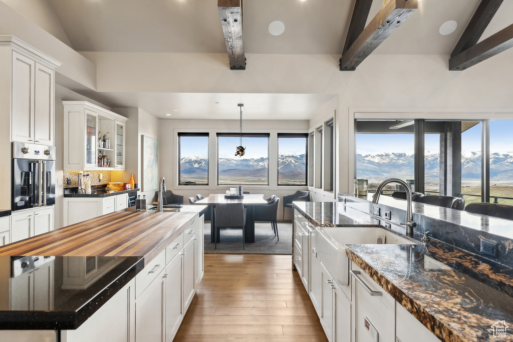 Kitchen featuring wall oven, light wood-style flooring, a mountain view, a sink, and white cabinets