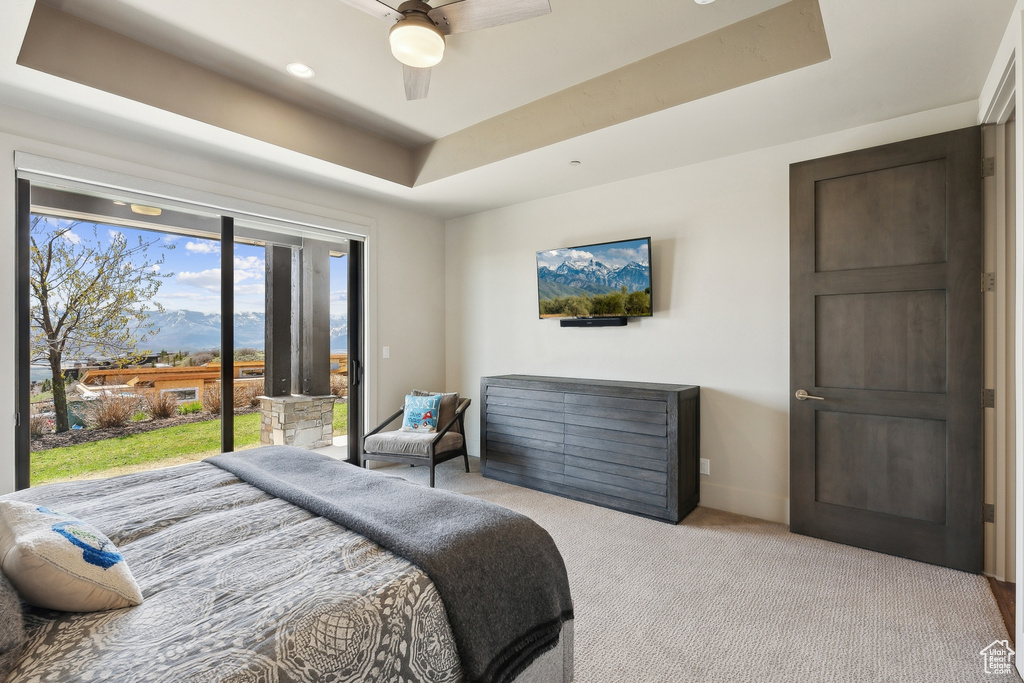 Bedroom featuring ceiling fan, carpet flooring, a tray ceiling, baseboards, and access to exterior