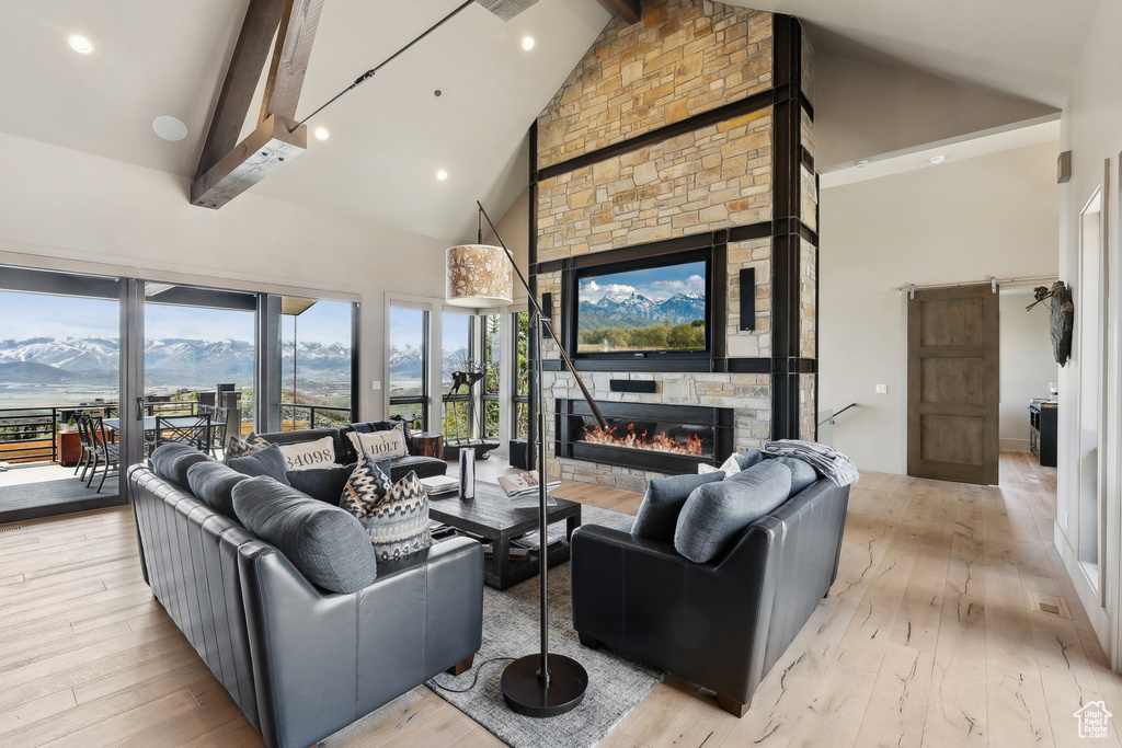 Living area with hardwood / wood-style flooring, a stone fireplace, beamed ceiling, and high vaulted ceiling