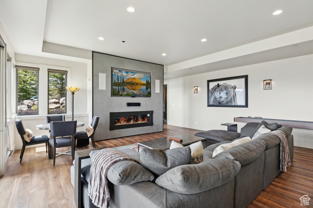 Living area with a large fireplace, wood finished floors, and recessed lighting