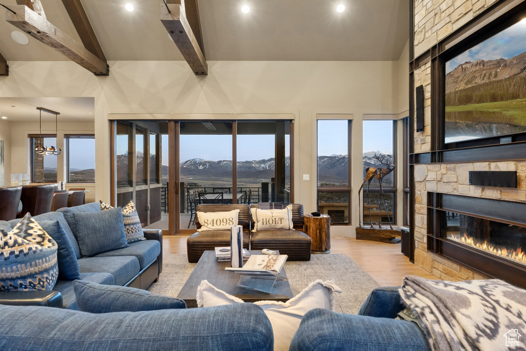 Living area featuring wood finished floors, beam ceiling, recessed lighting, a fireplace, and a high ceiling