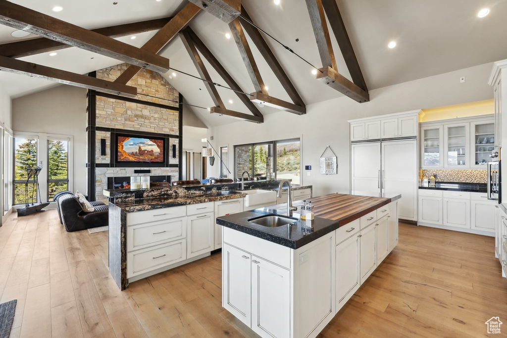 Kitchen with a sink, open floor plan, high vaulted ceiling, beamed ceiling, and a kitchen island with sink