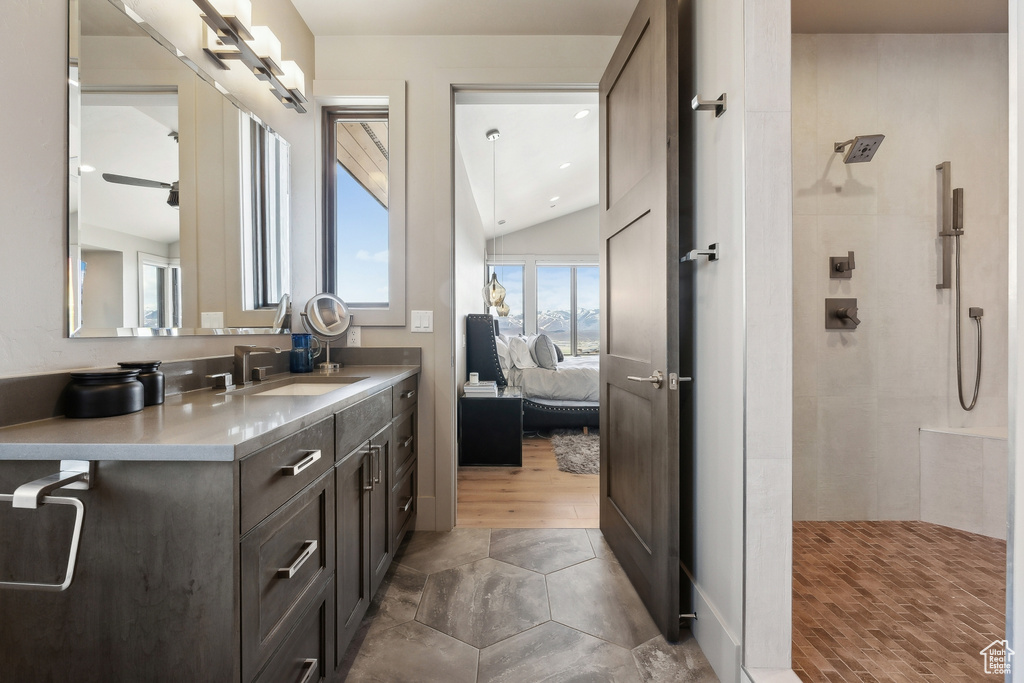 Ensuite bathroom featuring vanity, ensuite bathroom, lofted ceiling, and tiled shower