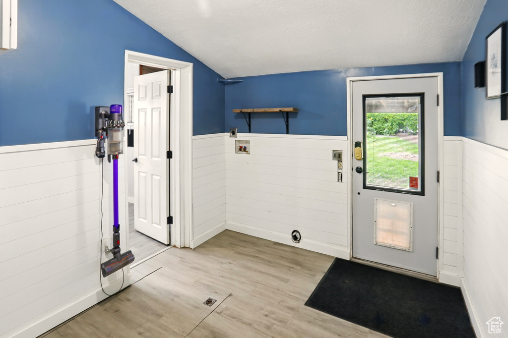 Entryway with vaulted ceiling, a wainscoted wall, wood finished floors, and wood walls