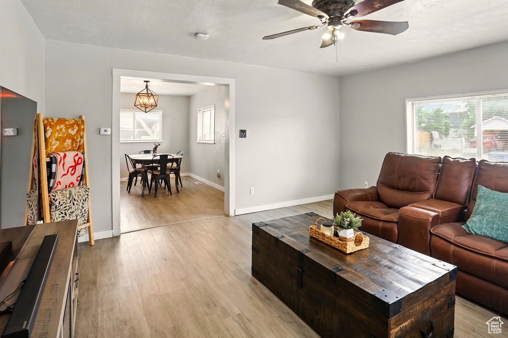 Living area featuring light wood-style floors, plenty of natural light, a ceiling fan, and baseboards