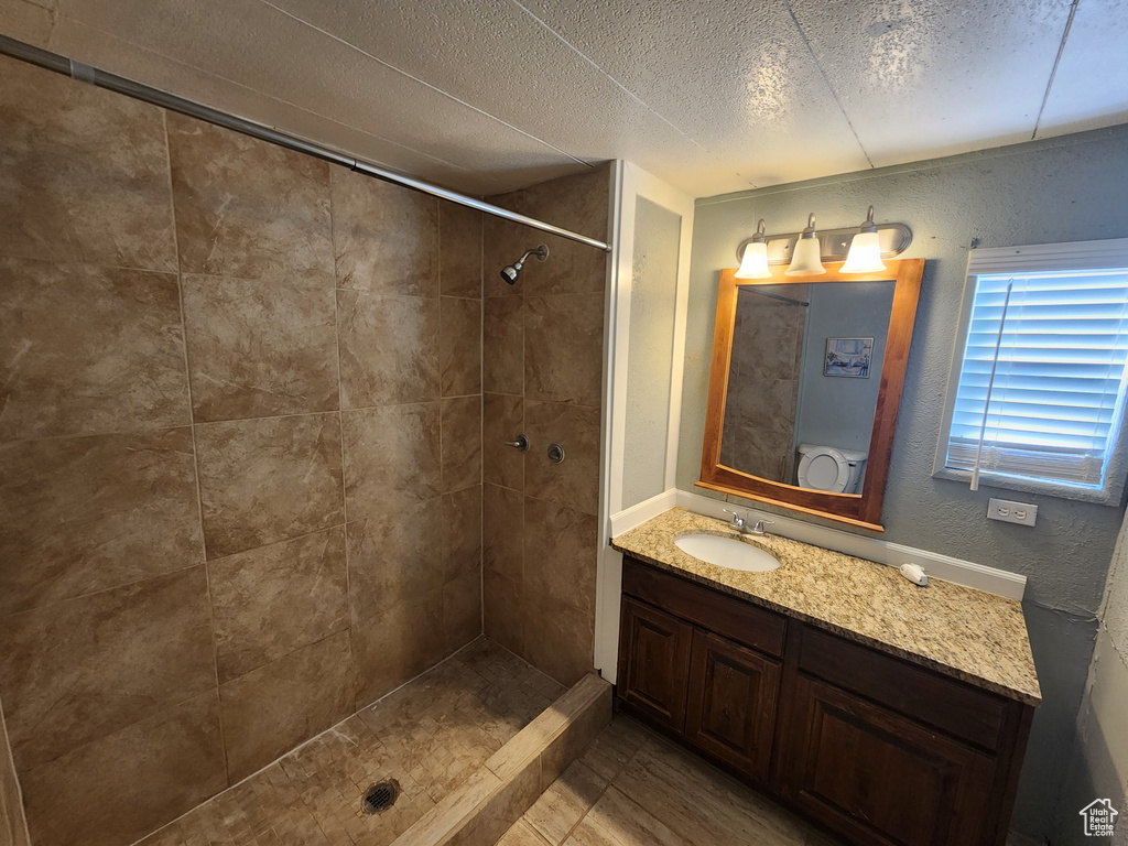 Bathroom with a tile shower, vanity, and a textured ceiling