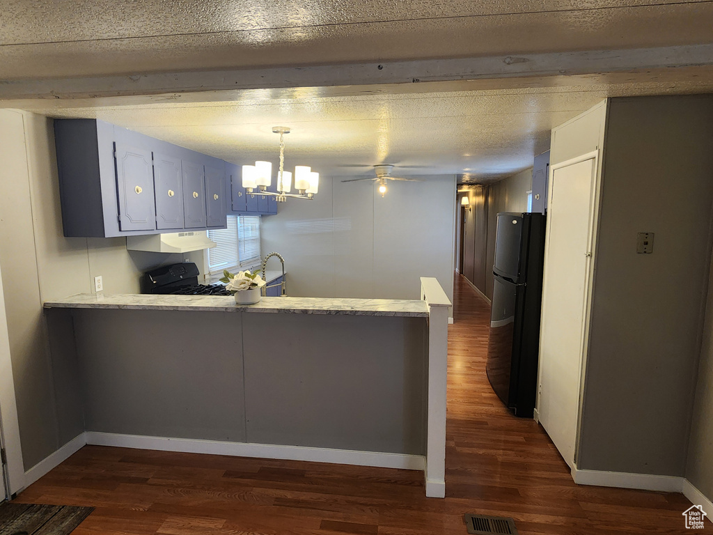 Kitchen featuring black appliances, a peninsula, dark wood finished floors, and a chandelier