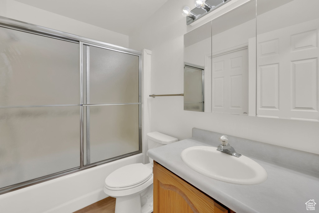 Full bathroom featuring vanity, toilet, and combined bath / shower with glass door