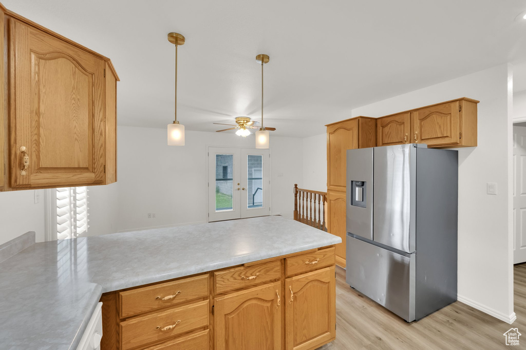 Kitchen with stainless steel refrigerator with ice dispenser, a peninsula, light wood-style floors, light countertops, and pendant lighting