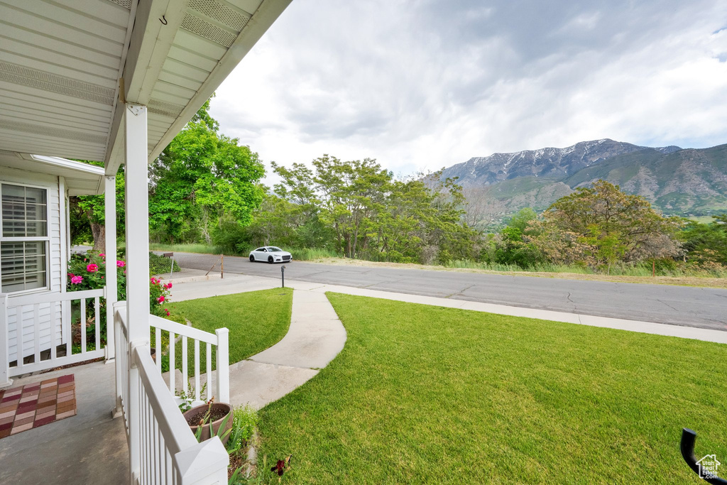 View of green lawn with a porch and a mountain view