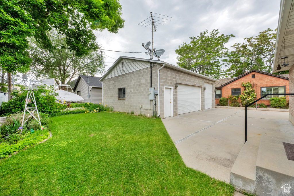 View of property exterior featuring a lawn, a detached garage, and concrete block siding