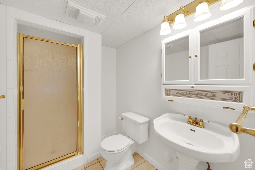 Full bathroom featuring a stall shower, tile patterned floors, toilet, and a sink