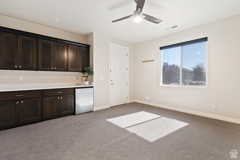 Kitchen featuring fridge, baseboards, carpet, a ceiling fan, and dark brown cabinets