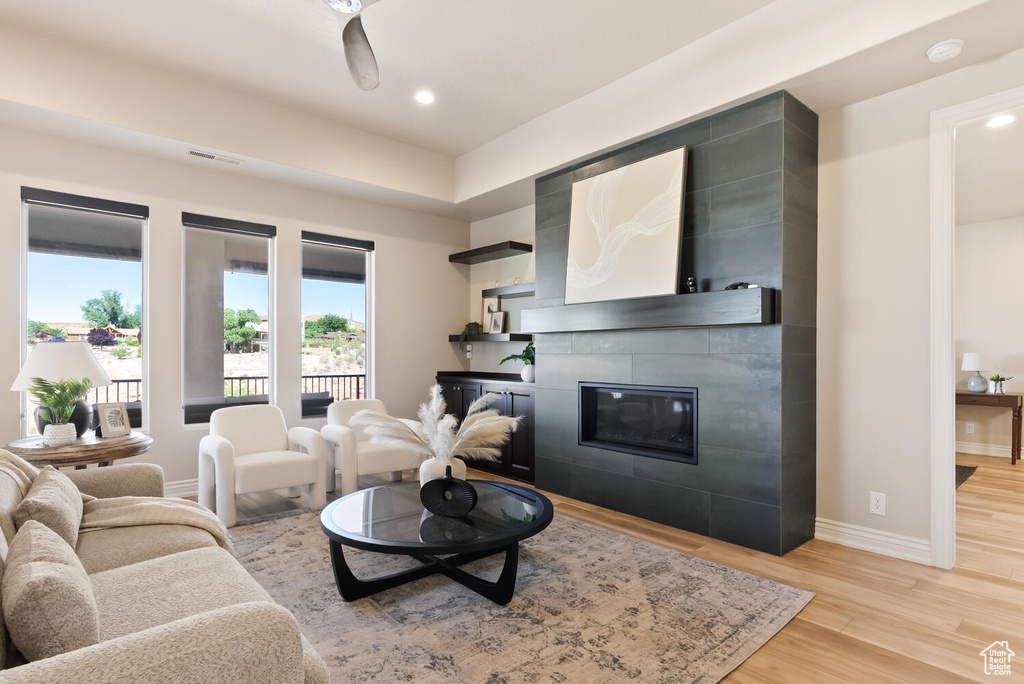 Living area with light wood-type flooring, a tiled fireplace, baseboards, and recessed lighting
