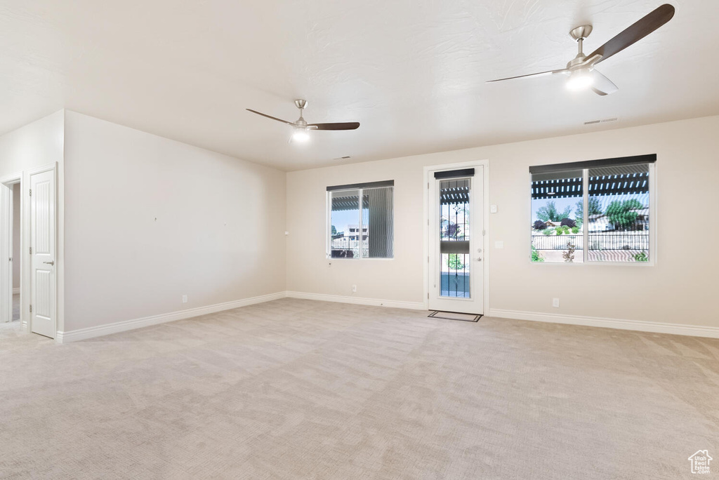 Empty room featuring ceiling fan, light carpet, and baseboards