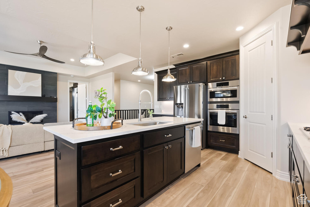 Kitchen featuring appliances with stainless steel finishes, a sink, light countertops, light wood-style flooring, and recessed lighting