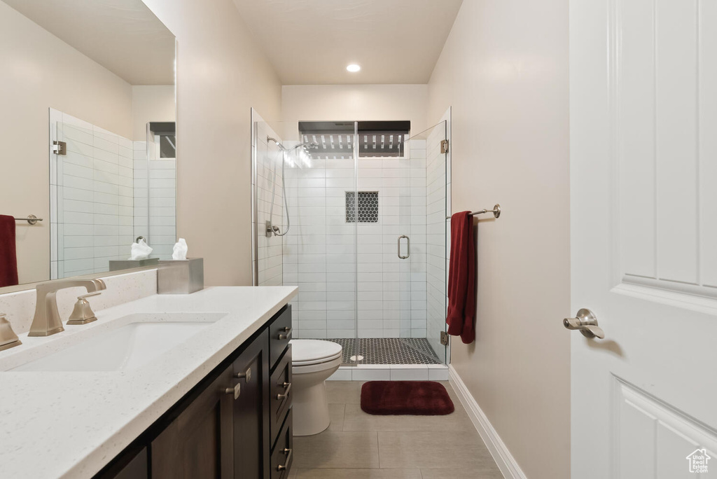 Bathroom featuring toilet, tile patterned floors, vanity, a shower stall, and baseboards