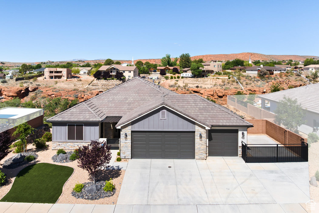 Single story home featuring board and batten siding, an attached garage, stone siding, and driveway
