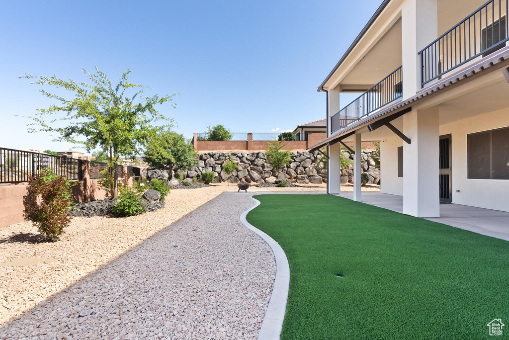 Fenced backyard featuring a balcony and a patio area