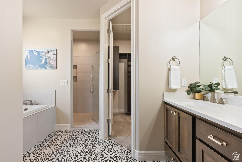 Full bathroom with a stall shower, a bath, vanity, tile patterned floors, and a walk in closet