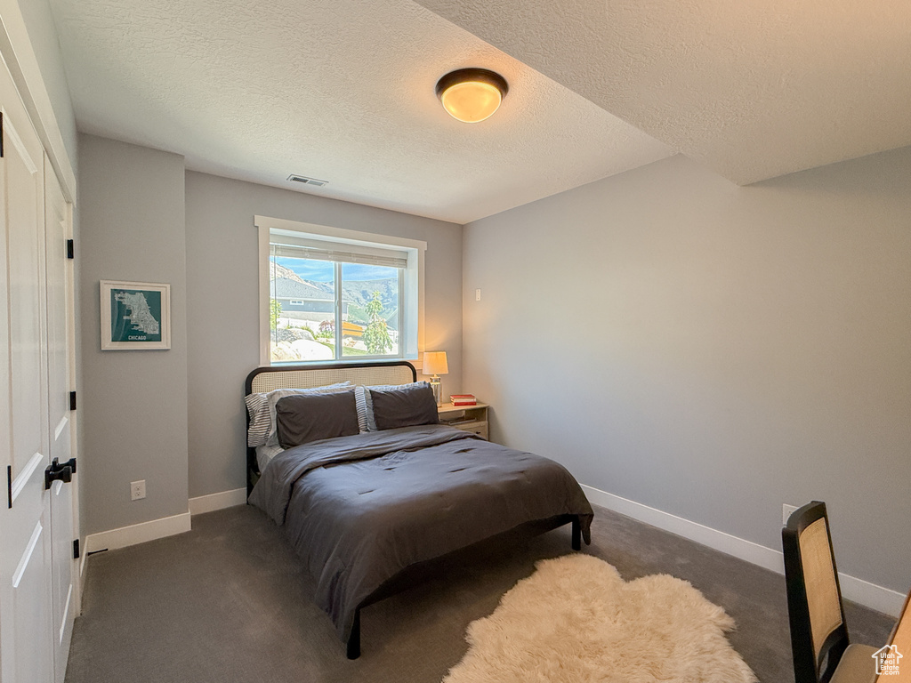 Carpeted bedroom with baseboards and a textured ceiling