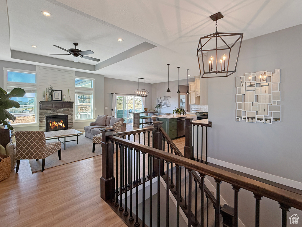 Hall with light wood-type flooring, an upstairs landing, a chandelier, recessed lighting, and a raised ceiling
