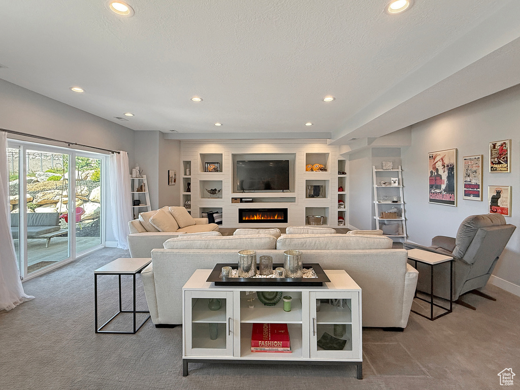 Carpeted living area featuring recessed lighting, baseboards, a lit fireplace, and built in shelves