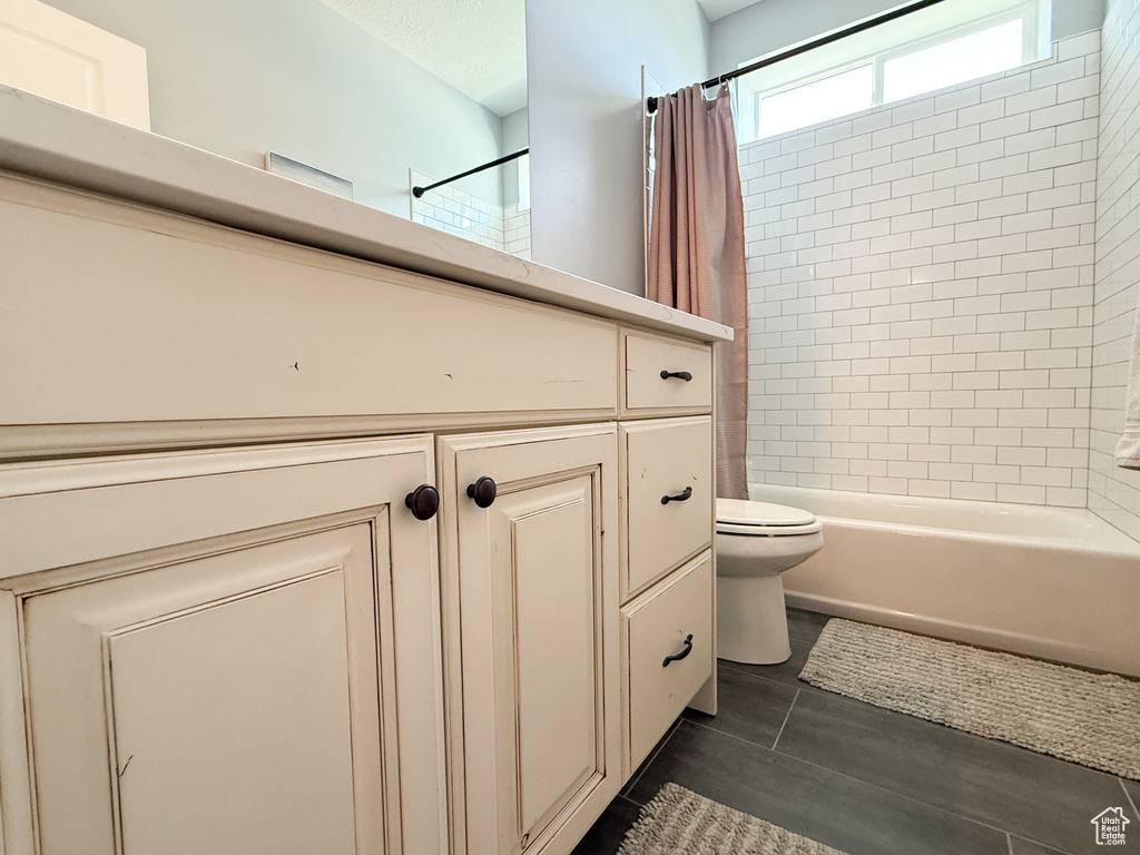 Bathroom with toilet, shower / tub combo with curtain, and vanity