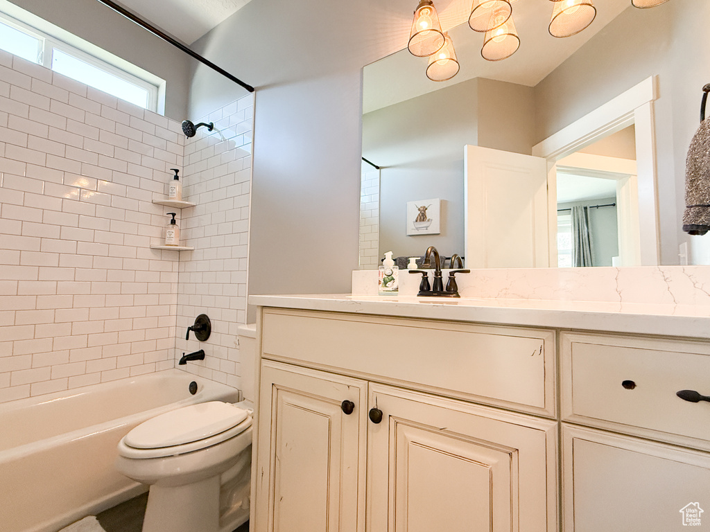 Bathroom with toilet, vanity, and  shower combination
