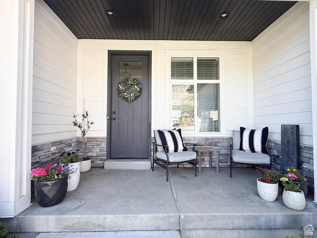 View of exterior entry featuring covered porch and stone siding