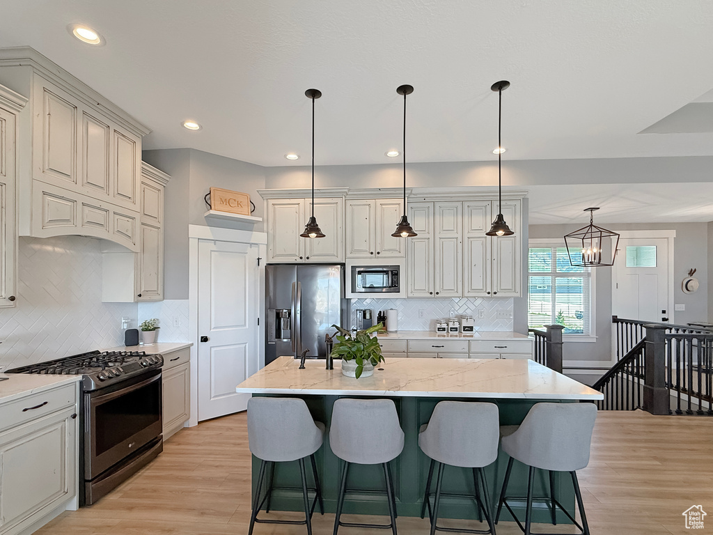 Kitchen with appliances with stainless steel finishes, light wood-style flooring, light stone countertops, decorative backsplash, and recessed lighting