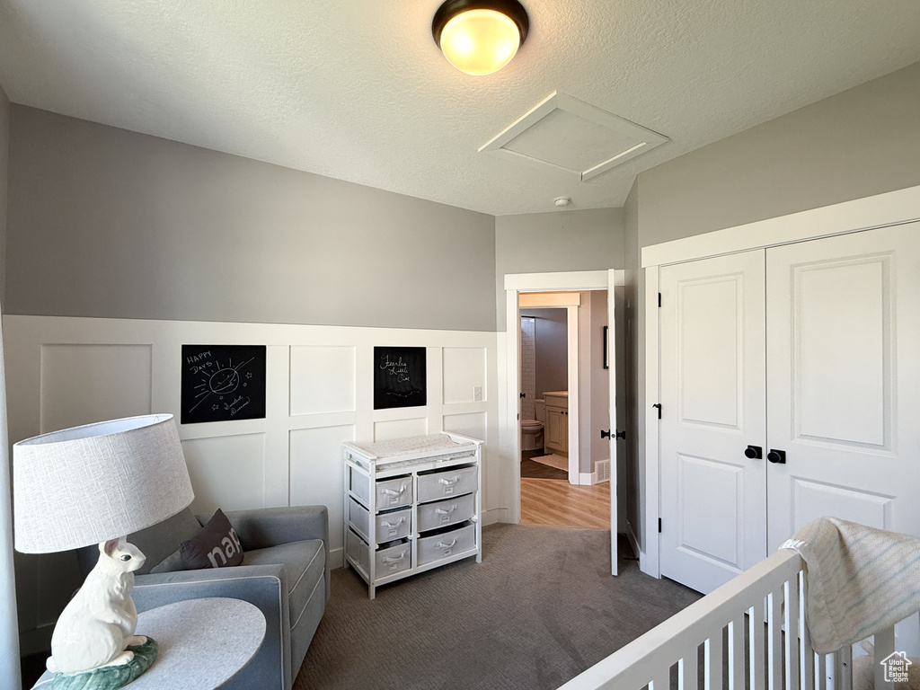 Bedroom featuring carpet, attic access, a closet, a decorative wall, and a wainscoted wall