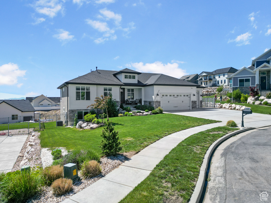 View of front of house featuring a residential view, stone siding, an attached garage, and concrete driveway