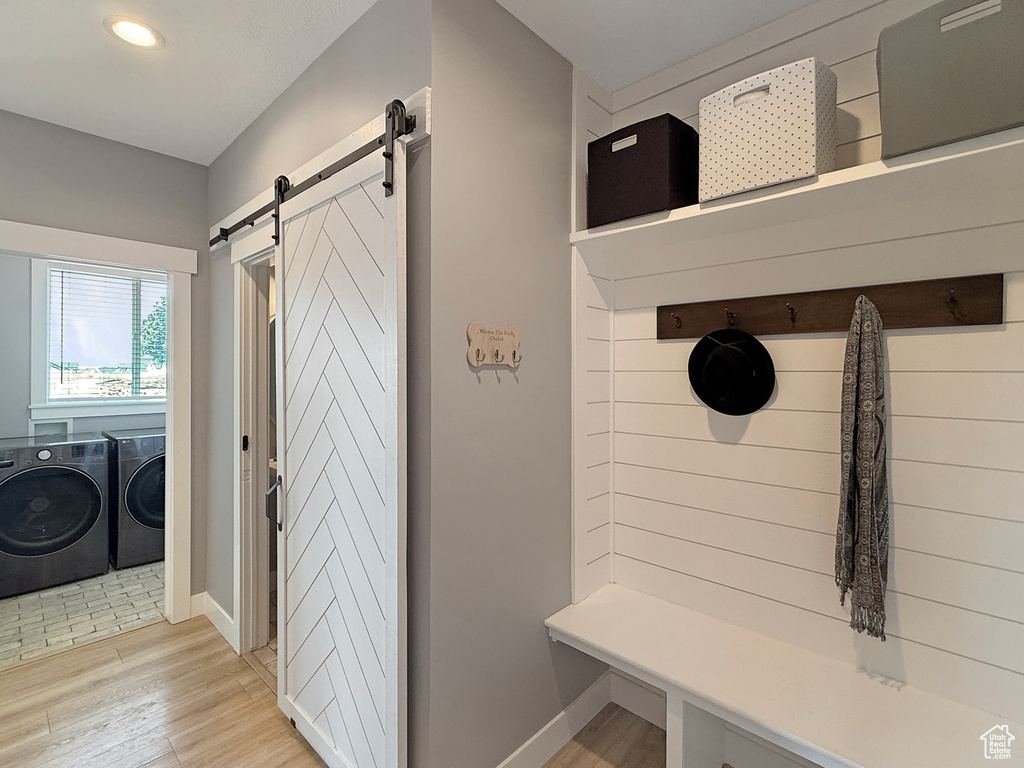 Mudroom featuring a barn door, washer and clothes dryer, baseboards, light wood-style floors, and recessed lighting