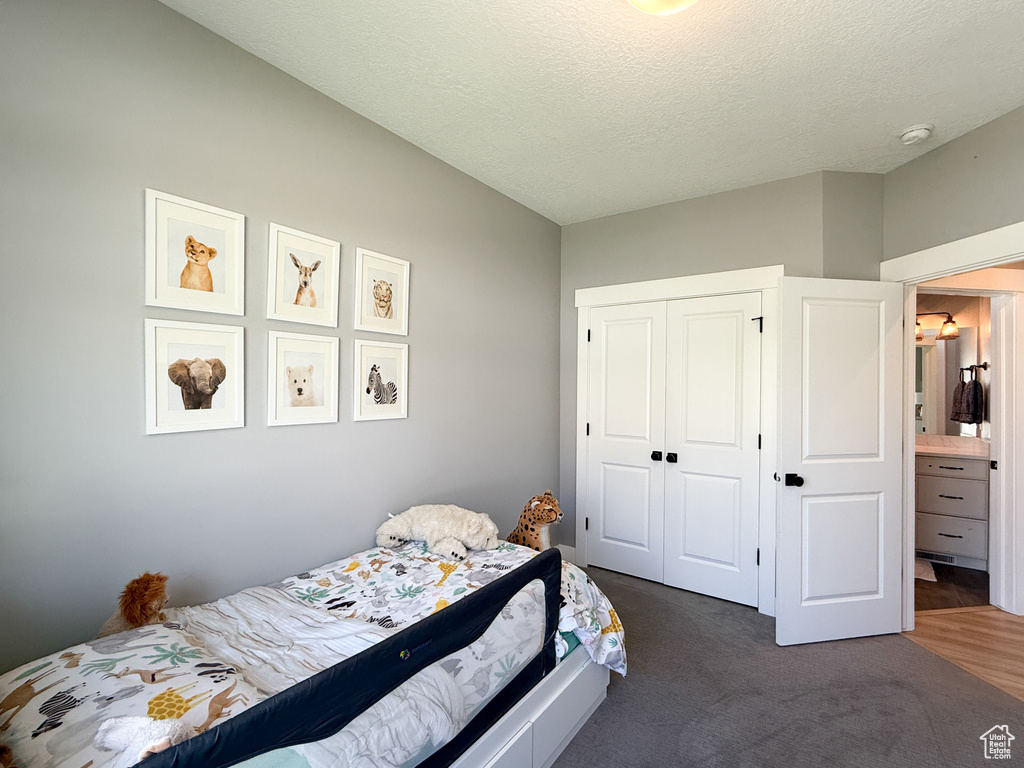 Bedroom with a closet, a textured ceiling, and dark colored carpet