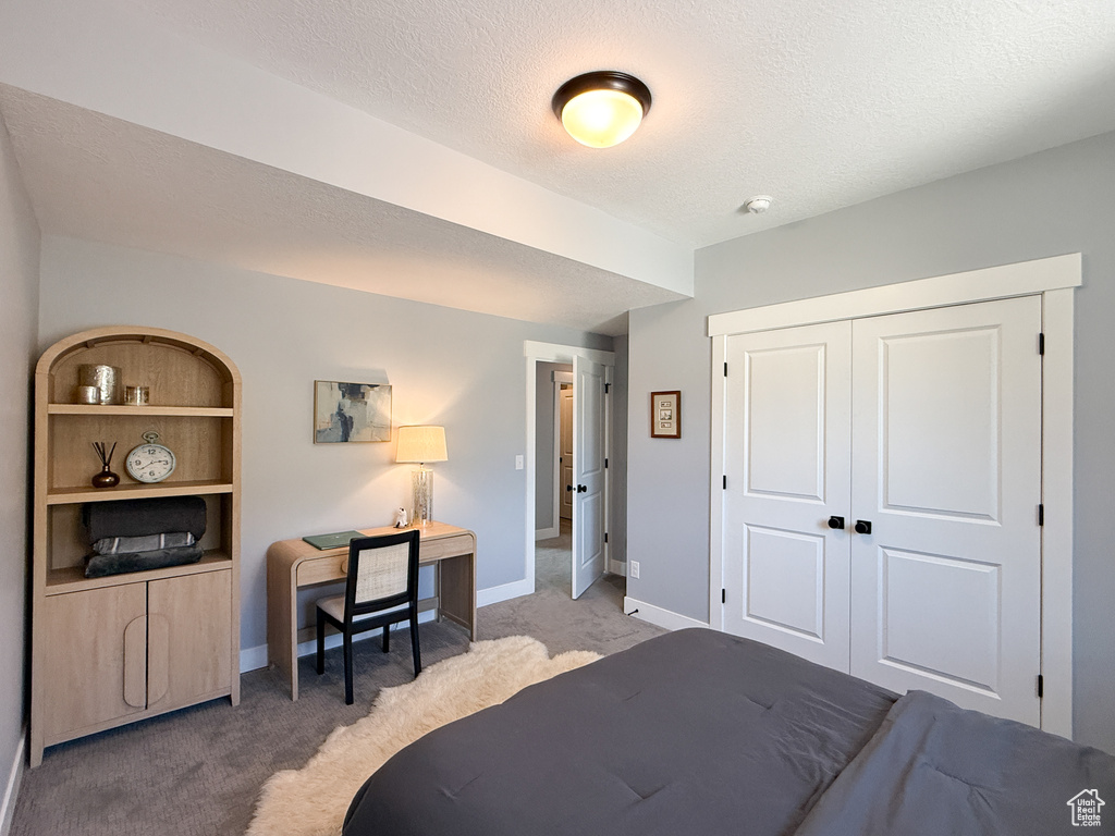 Bedroom with light colored carpet, baseboards, a closet, and a textured ceiling
