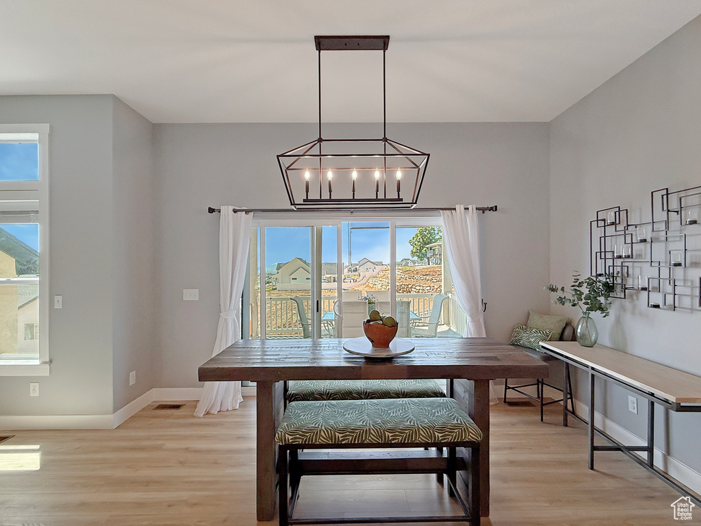 Dining space with light wood-style floors, baseboards, and a chandelier