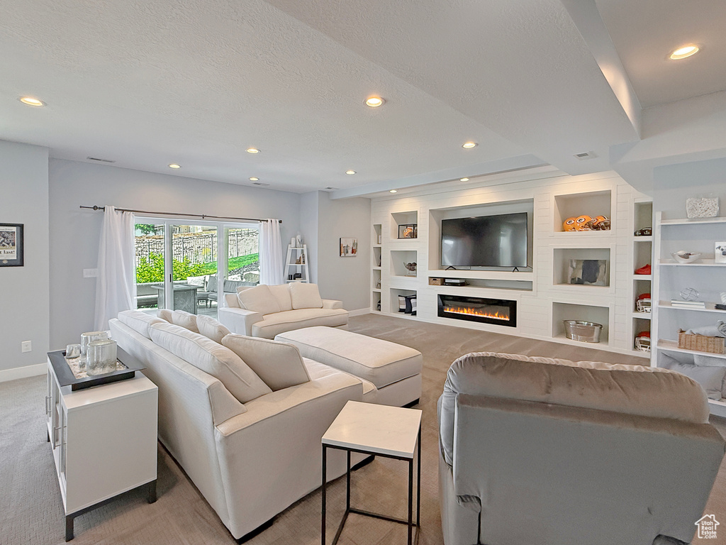Living area with built in shelves, baseboards, light carpet, recessed lighting, and a large fireplace